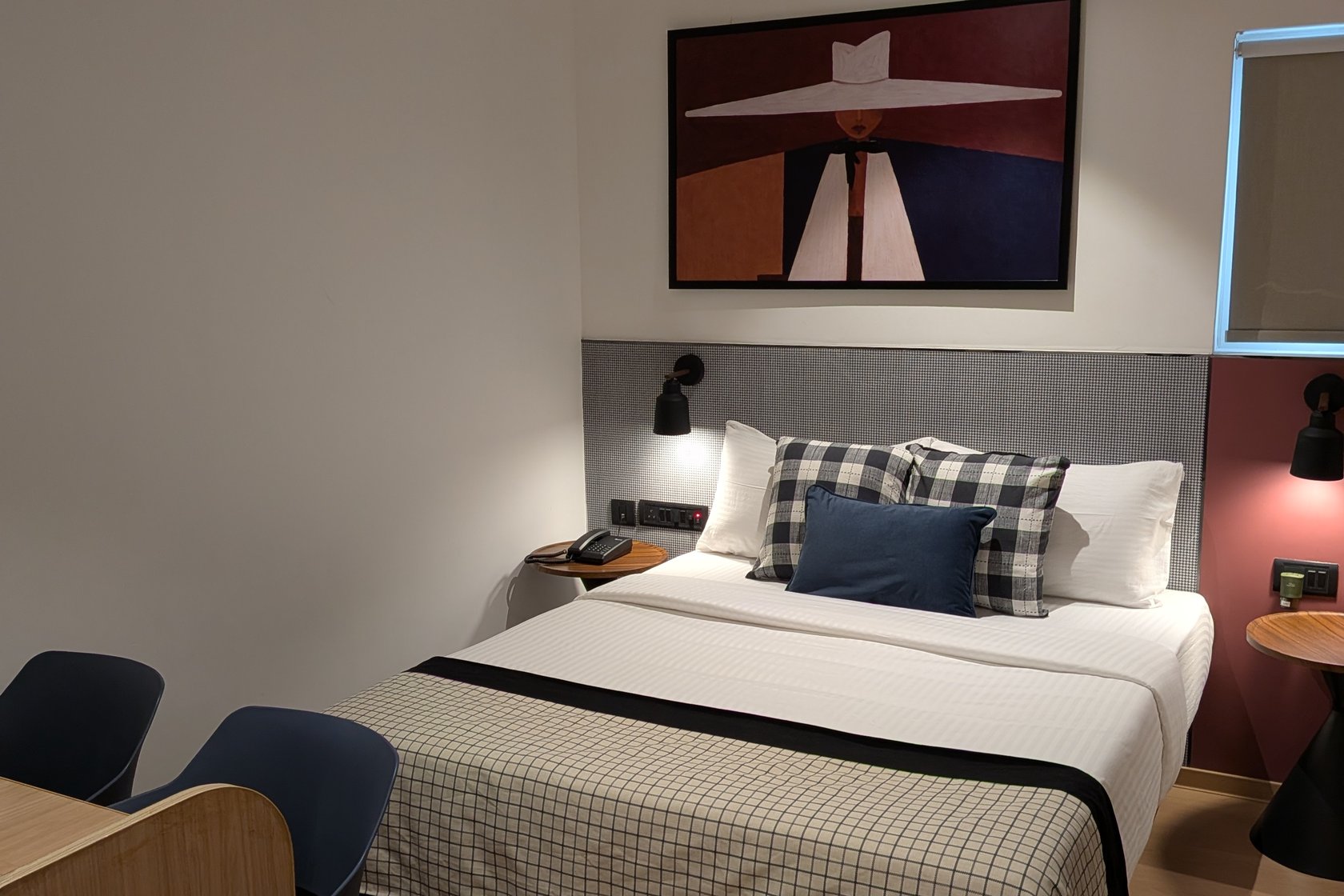 Deluxe Triple Room at The Roost — queen bed under a framed print, with a seating corner