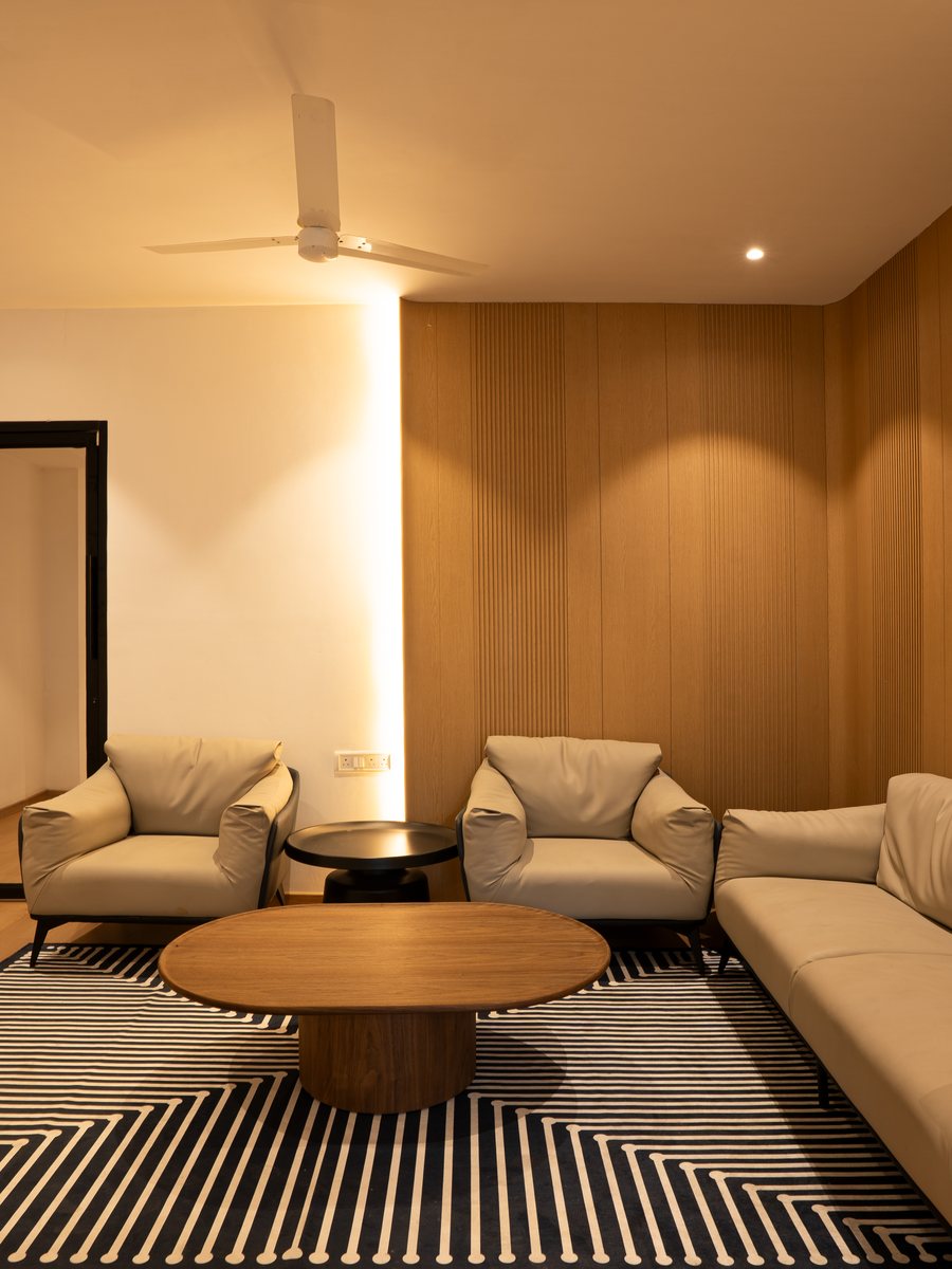 The lounge at The Roost — leather armchairs, a low oak table and warm cove lighting against a fluted wood wall